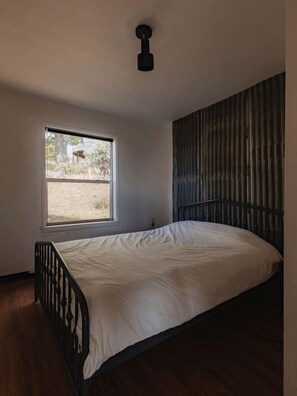 A bedroom with a single bed, a window, a metal headboard, and a ceiling light fixture. - Off-Grid, Rustic, Two Bedroom Cabin Nestled in the Sequoias, Perfect for a Weekend to Disconnect in Nature (Dunlap)