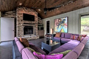 Una sala de estar con chimenea de piedra, un conjunto de sofá y un cuadro grande.
