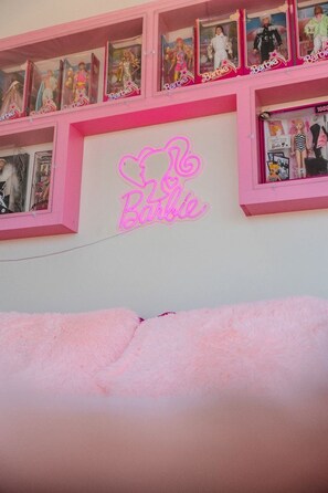Un senyal de neó amb la paraula 'Barbie' i una estant plena de nines Barbie.
