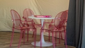 A tent with a table and four chairs, a window, and a curtain.