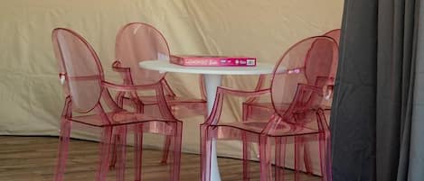A tent with a table and four chairs, a window, and a curtain.