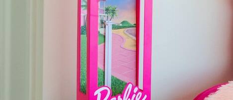 Una scatola rosa di Barbie su uno scaffale bianco.