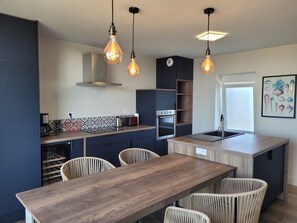 Una cocina moderna con una isla central, electrodomésticos integrados e iluminación colgante.