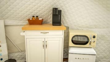 A kitchenette with a microwave, a small refrigerator, and a cabinet with a basket of items.