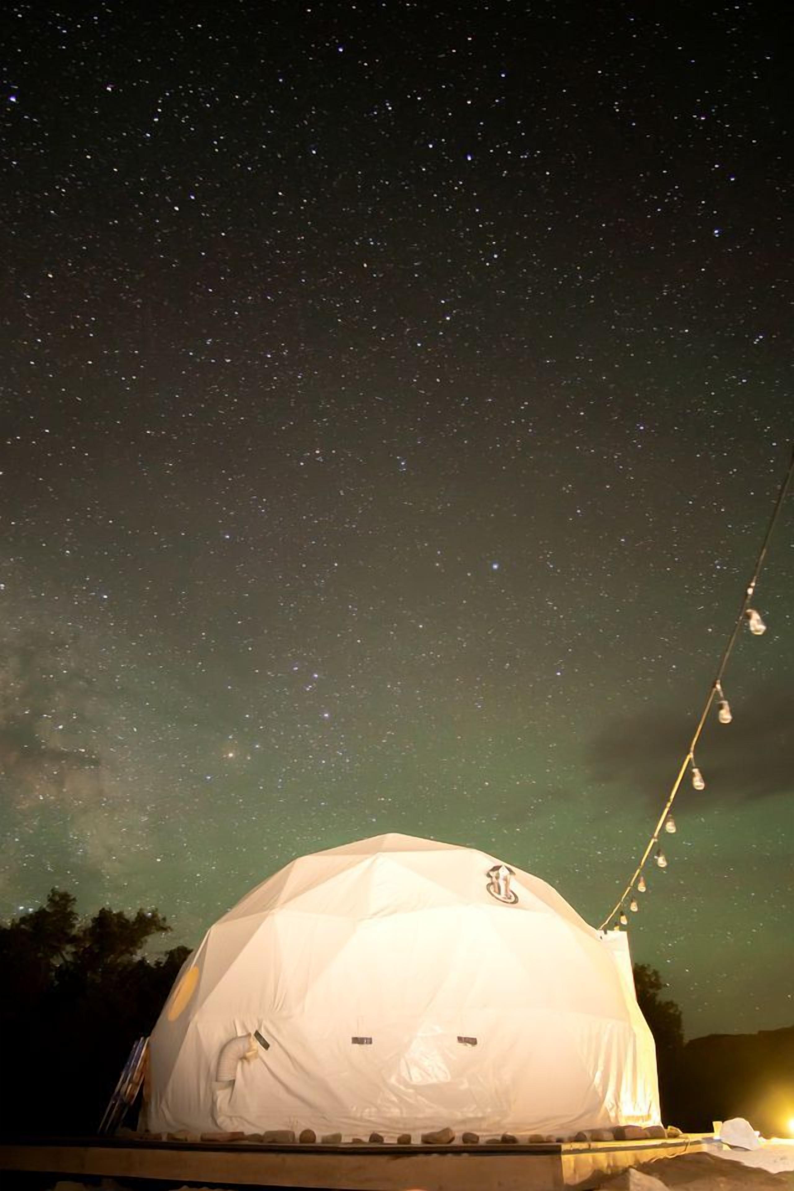 A dome-shaped tent under a starry night sky.