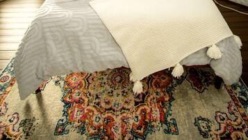 A bedroom with a bed, a bedside table, a lamp, and a patterned rug.