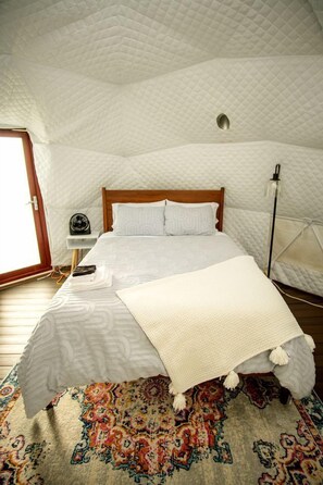 Une chambre à coucher avec un lit, une table de chevet, une lampe et un tapis à motifs.