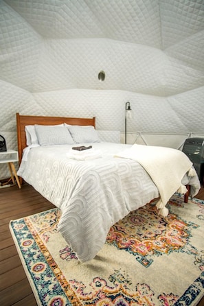 Une chambre à coucher avec un lit, une table de chevet, une lampe et un tapis à motifs.