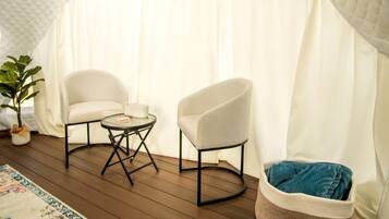 A cozy room with a quilted ceiling, two chairs, a small table, a colorful rug, and a bean bag.