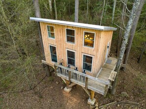 Una cabaña de madera con varias ventanas, una terraza y un paisaje boscoso.