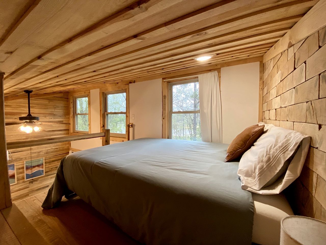 Ein Schlafzimmer mit Holzboden, einem Bett mit Kissen und einem Fenster.
