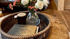 A room with a bed, a vase with flowers, a tray with a book and a mug, and a wooden wall.