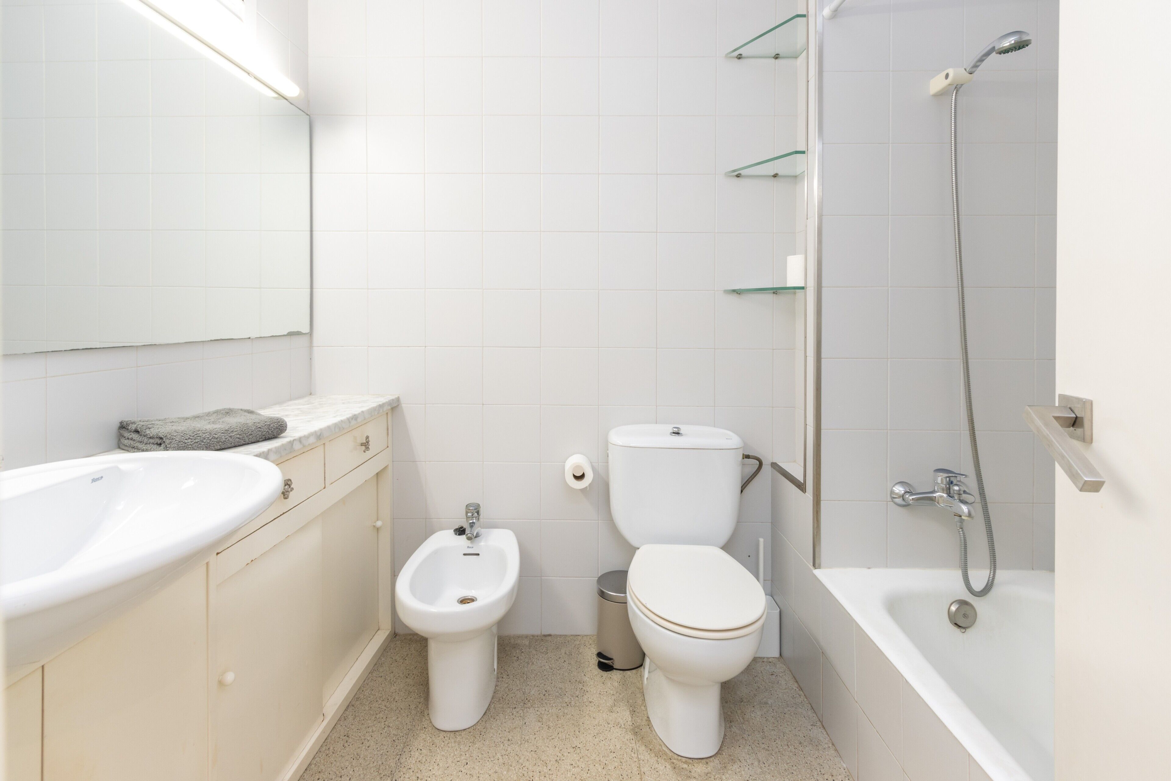 A bathroom with a sink, bidet, toilet, and bathtub.