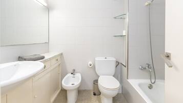 A bathroom with a sink, bidet, toilet, and bathtub.