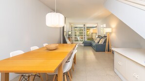 Un espace de salle à manger moderne avec une table en bois, des chaises blanches et un luminaire suspendu.