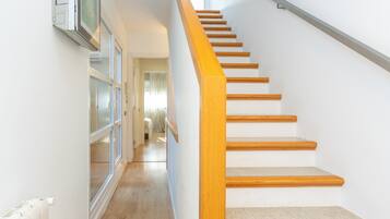 Una escalera de madera con barandilla que lleva a una habitación con radiador y ventana.