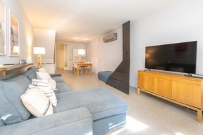 A modern living room with a sofa, TV, and wooden cabinet. - Holiday Home 'Siker' with Private Terrace and Wi-Fi (Banyoles)