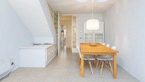 Une cuisine moderne avec des meubles blancs, une table à manger en bois et un luminaire suspendu.