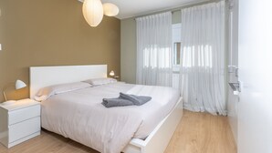 Une chambre moderne avec un lit, des tables de chevet, une lampe et une fenêtre avec des rideaux.