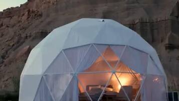 A geodesic dome tent with a view of a rocky mountain in the background.