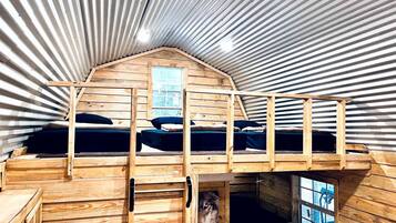 A wooden interior with bunk beds, a window, and a small enclosed area with a bench.