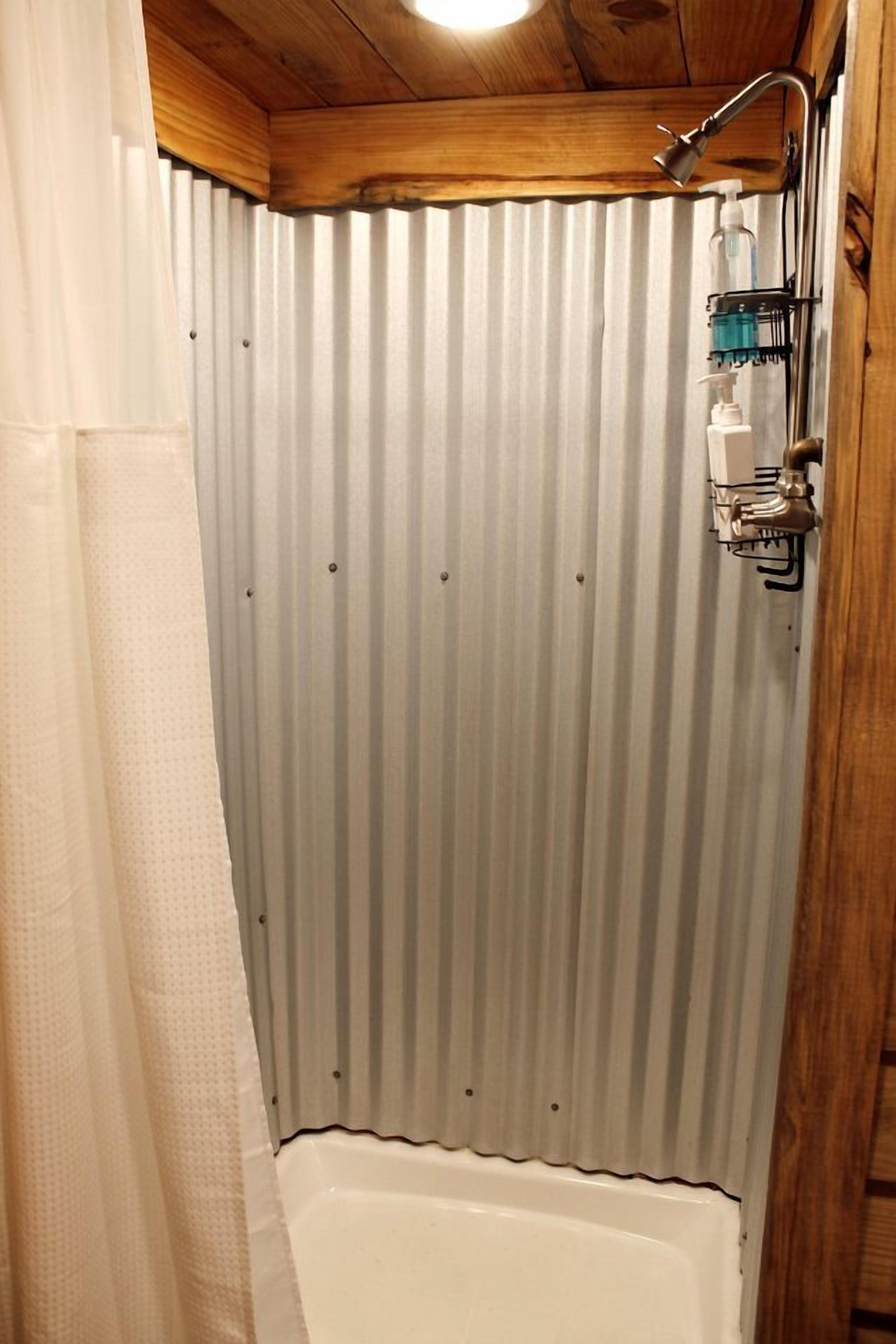 A shower with a wooden ceiling, a corrugated metal wall, and a handheld showerhead.