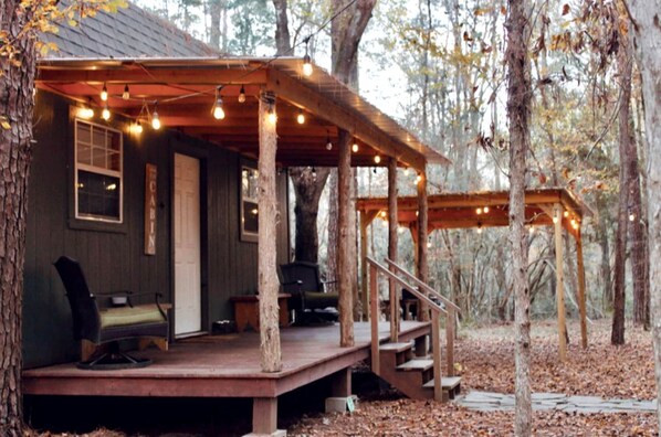 A cabin with a porch, outdoor seating, and a staircase leading to the entrance.