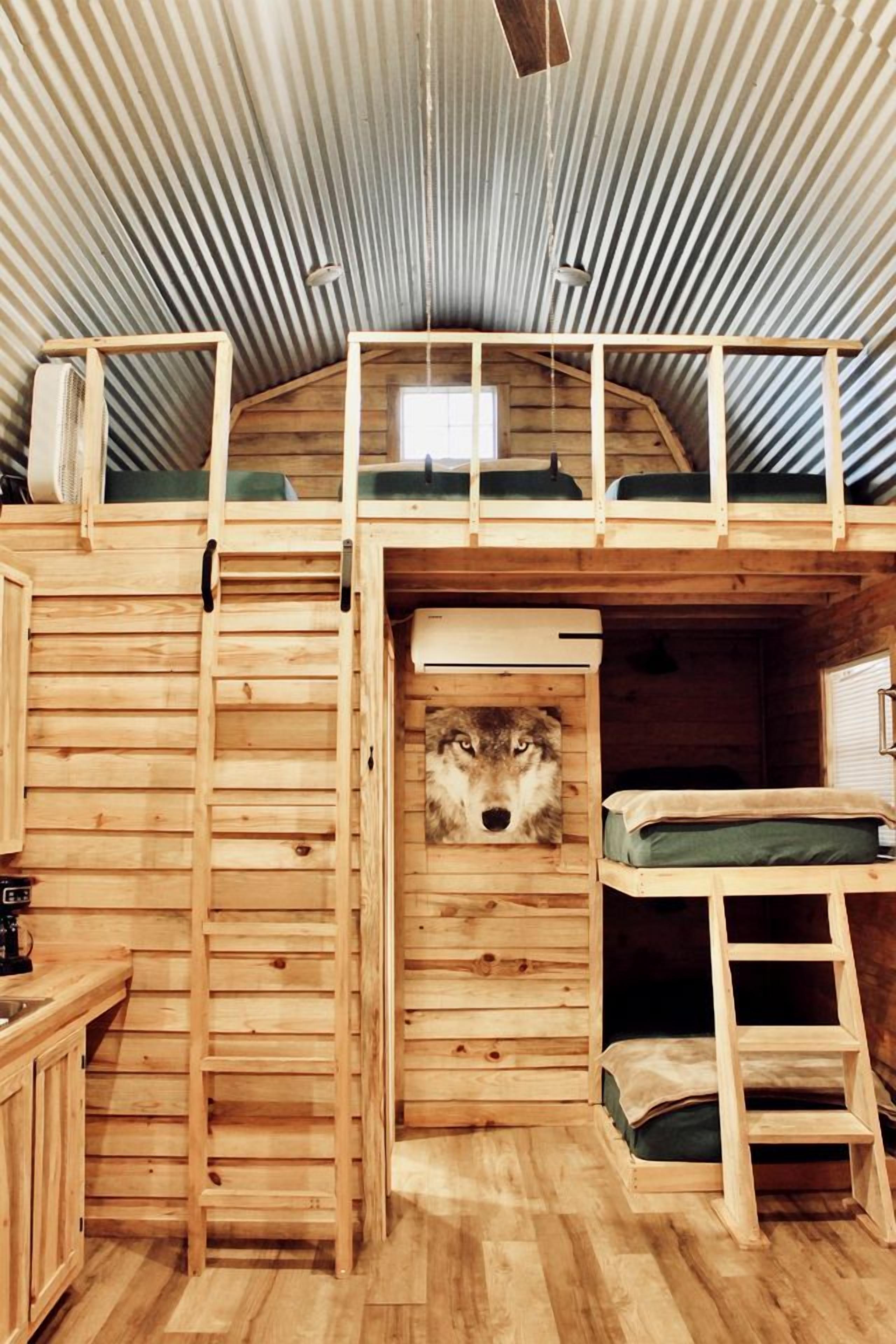 A wooden cabin with a loft bed, a ladder, and a wolf head decoration.