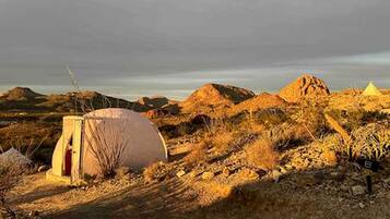 Een tent in een woestijnlandschap met rotsachtig terrein en schaarse begroeiing.