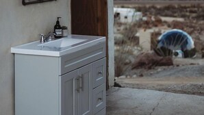 Un bagno con un lavandino bianco, uno specchio e vista su un paesaggio desertico.