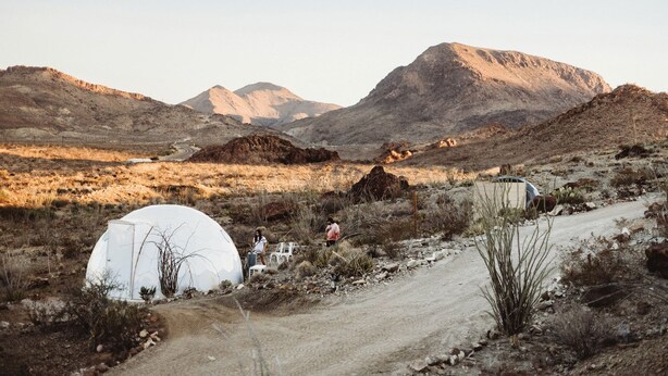 A desert landscape with tents and a dirt road.