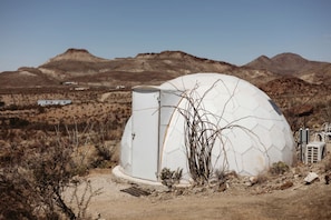 Una estructura en forma de cúpula en un paisaje desértico, con montañas al fondo.