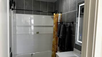 A bathroom with a bathtub, toilet, and a shower curtain.