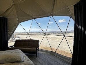 Una habitación con tienda, una cama, un sofá y vistas a un paisaje seco.