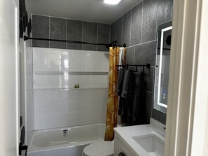 A bathroom with a bathtub, toilet, and a shower curtain.