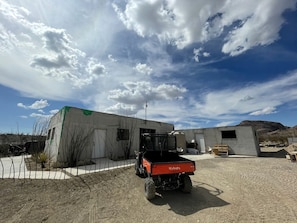 A Kubota vehicle parked in a semi-urban area with buildings and a clear sky.