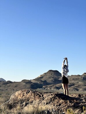 A person standing on a rocky outcrop with a clear sky in the background.