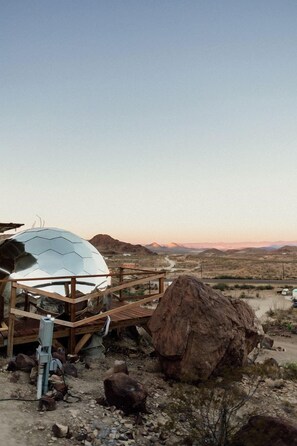 A spherical structure with a wooden deck, surrounded by desert landscape and mountains. - Impressive Dome with Great Panoramic Desert Views in Terlingua, Texas (Terlingua)