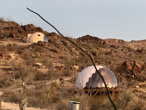 Two spherical structures in a desert landscape with rocky terrain and sparse vegetation.