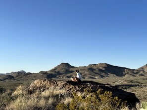 A person sitting on a rock with a mountainous landscape in the background. - Impressive Dome with Great Panoramic Desert Views in Terlingua, Texas (Terlingua)