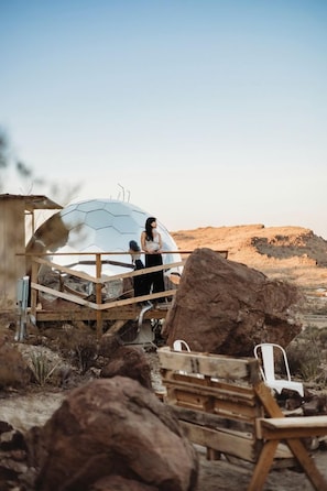 A geodesic dome structure with a wooden deck, large rocks, and a clear sky. - Impressive Dome with Great Panoramic Desert Views in Terlingua, Texas (Terlingua)