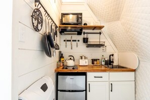 A compact kitchen with a microwave, kettle, and refrigerator.