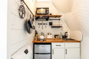 A compact kitchen with a microwave, kettle, and refrigerator.