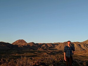 A person standing in a mountainous landscape with clear skies.