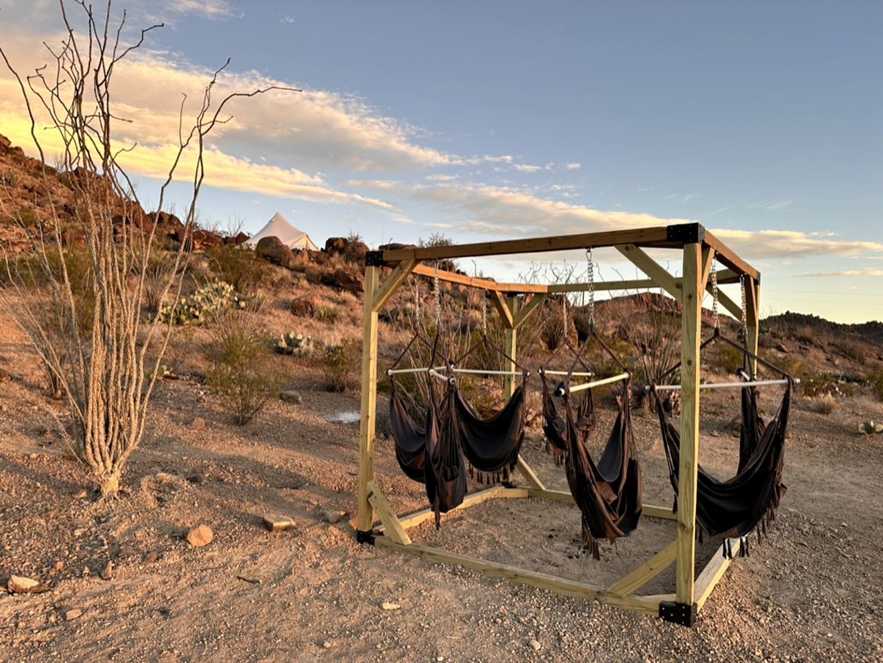 A hammock structure in a desert setting with rocky terrain and sparse vegetation.