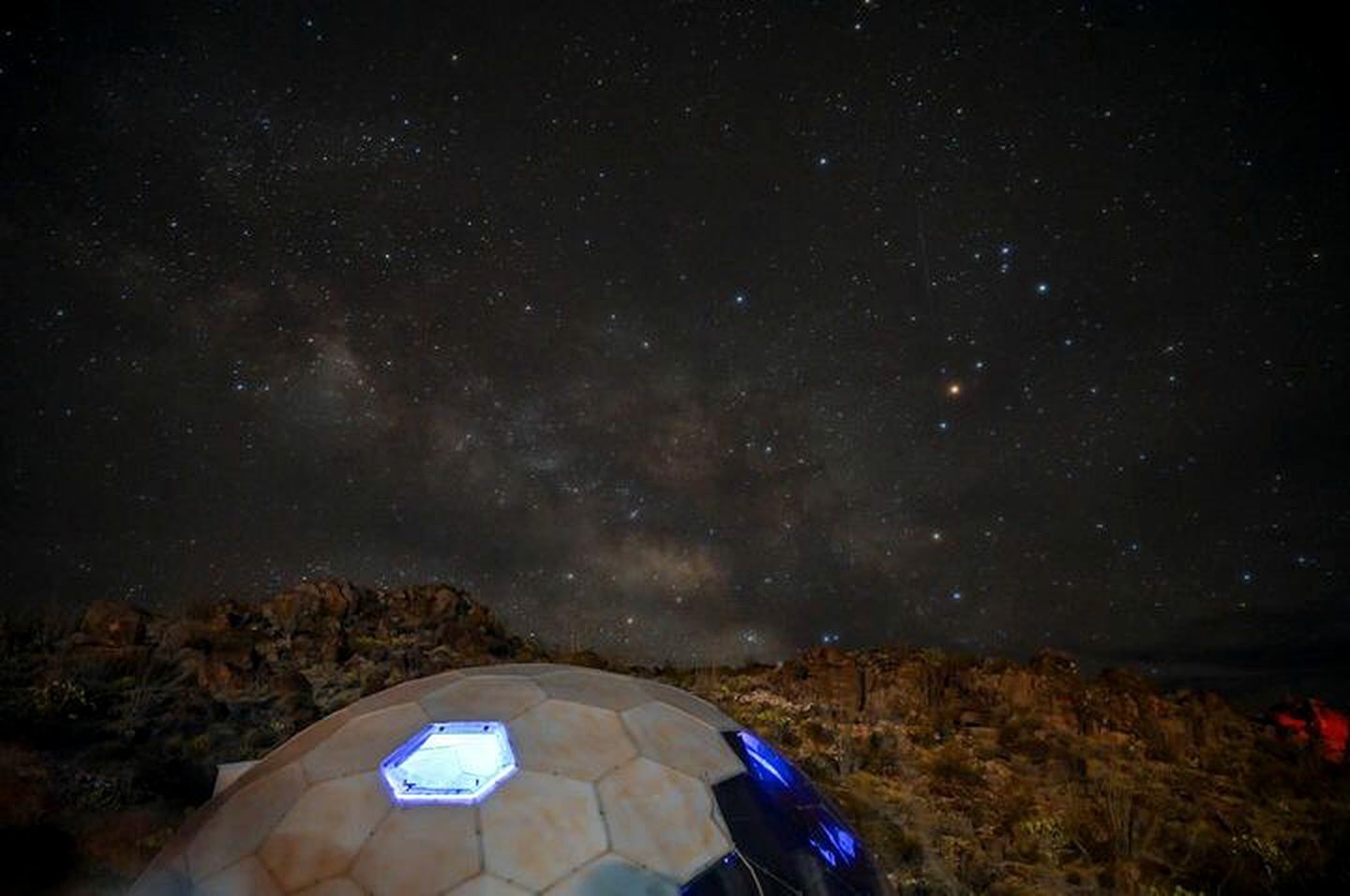 Une structure en forme de dôme, dotée d’une base hexagonale, d’une source de lumière centrale et reproduisant un ciel étoilé.