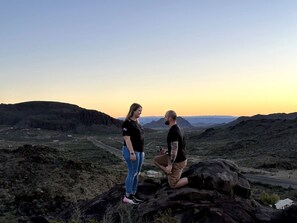 A couple on a rocky outcrop with a view of a desert landscape.