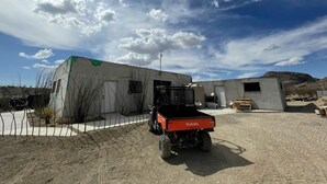 Ein Kubota Fahrzeug in einer halbstädtischen Umgebung mit Gebäuden und blauem Himmel.