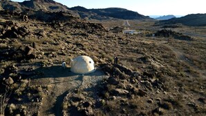 Ett stenigt landskap med en sfärisk formation och en grusväg.