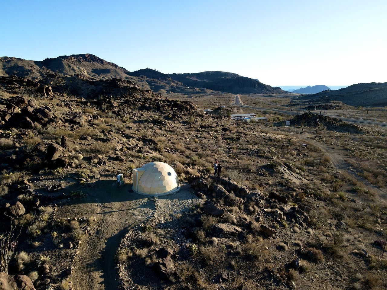 Un paysage rocheux avec une structure sphérique et un chemin de terre.